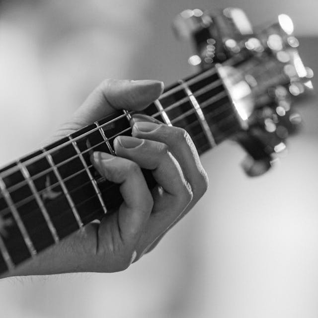 Close up of hand playing guitar in black and white | Image by Photo by Biekir: https://www.pexels.com/photo/close-up-of-hand-playing-guitar-in-black-and-white-31309915/