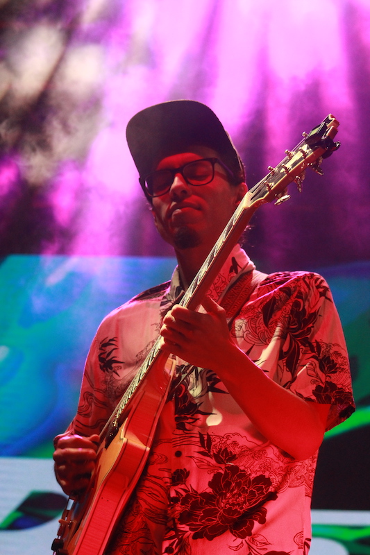 Roger Vargas playing electric guitar onstage with backlighting